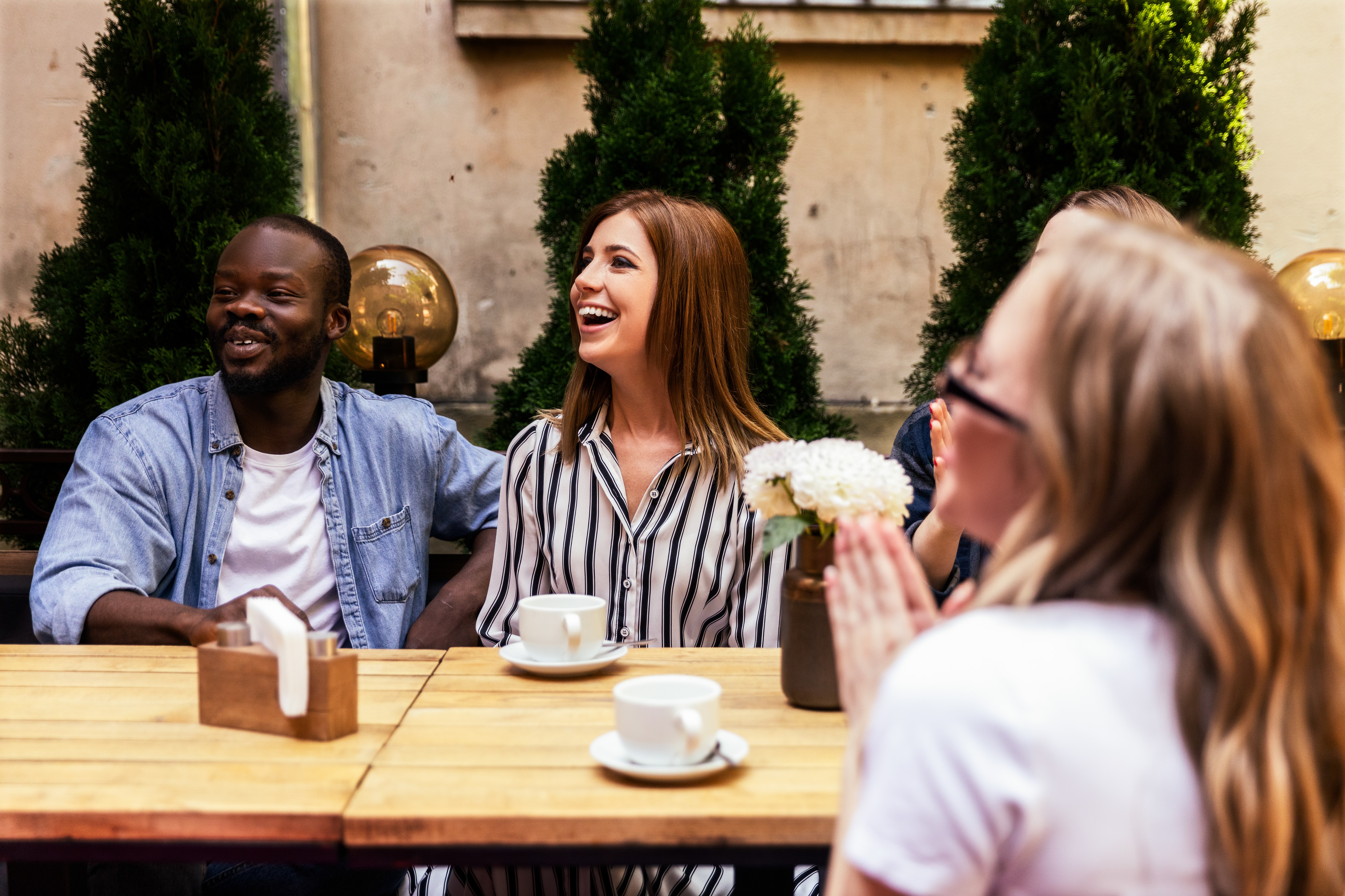 african-boy-caucasian-girls-are-laughing-cosy-open-air-cafe-hot-sunny-day