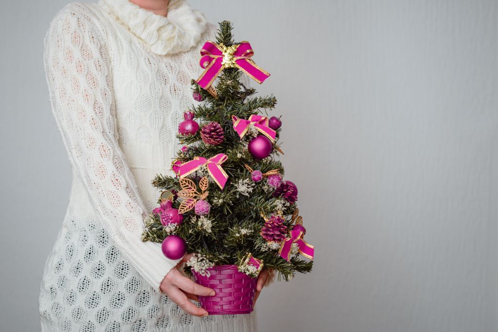 closeup-of-white-woman-holding-tiny-christmas-tree-in-pot-with-purple-decorations